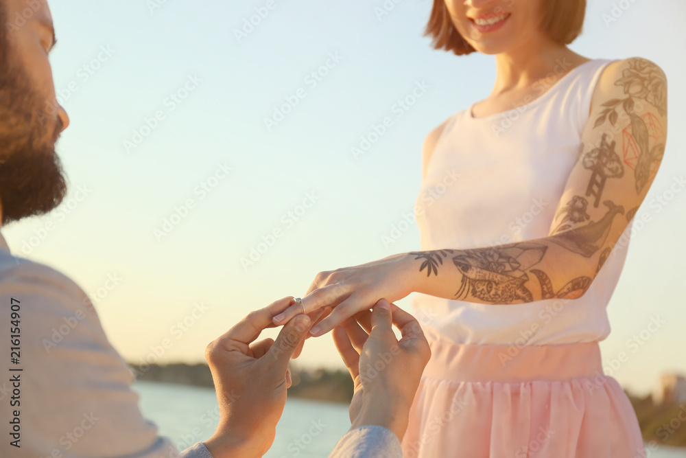 男子在户外将美丽的订婚戒指戴在心爱的人的手上