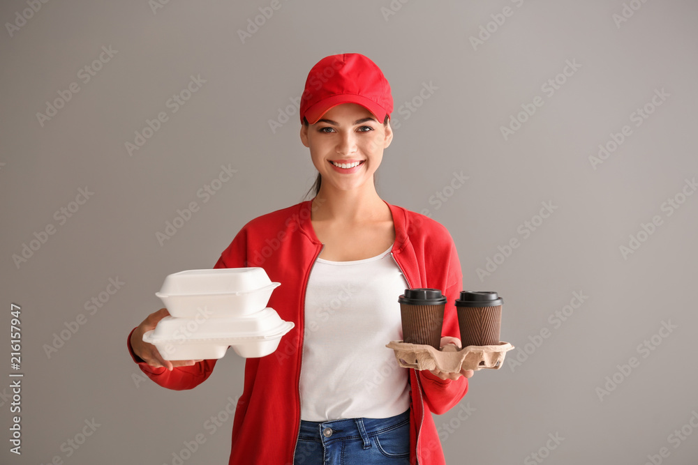 年轻女子，灰色背景，拿着塑料容器和咖啡杯。送餐服务