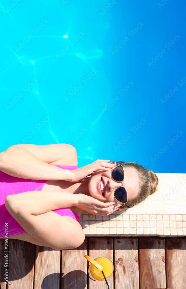 美丽的年轻女子在游泳池附近休息