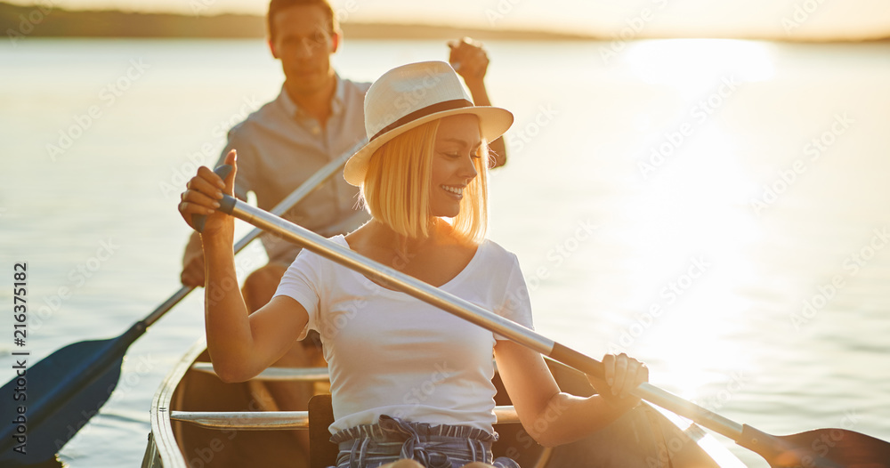 微笑的年轻夫妇在夏天的下午划独木舟