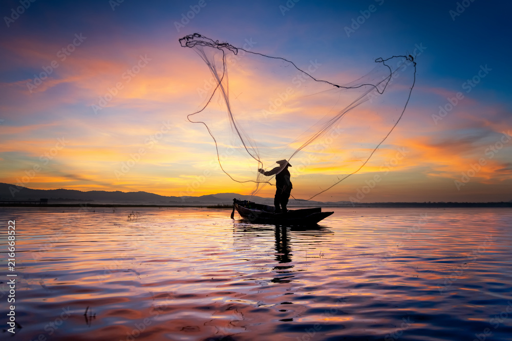 缅甸渔民在木船上的剪影，缅甸渔民在捕捉淡水鱼
