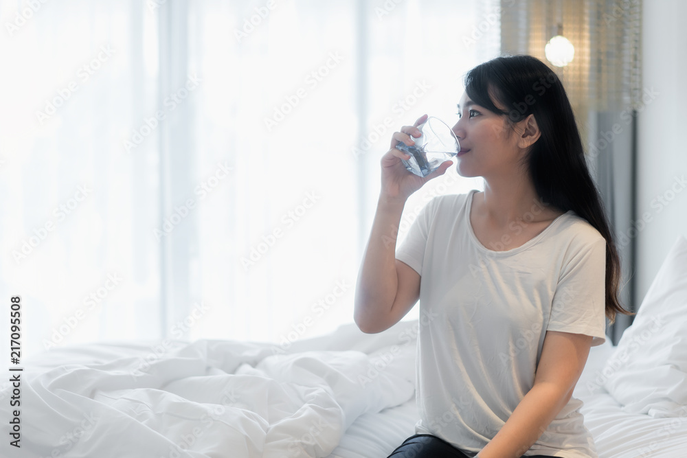 亚洲女人早上醒来后喝水。