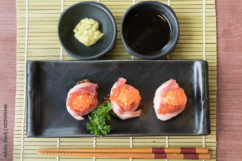 黑色盘子里的滨湖寿司三文鱼卷，配日本酱汁和绿叶装饰，日本