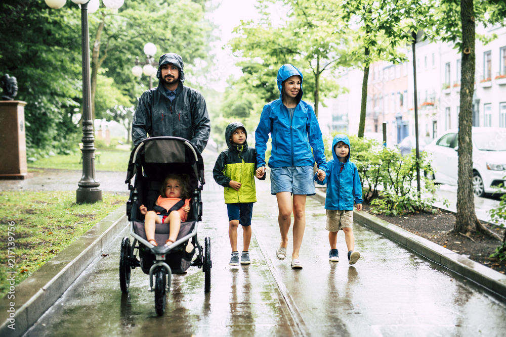 带孩子的家人穿着雨衣在雨天行走