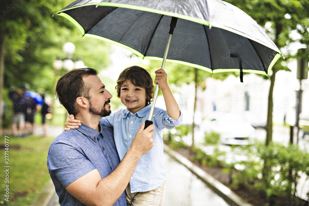下雨天，爸爸和孩子在公园里打着伞