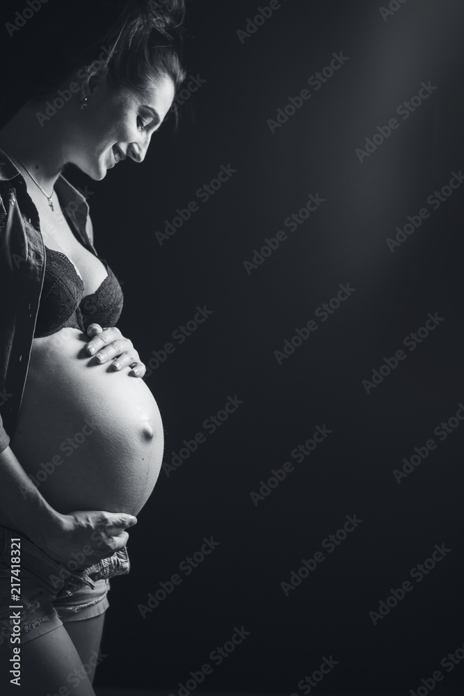 美丽的年轻孕妇黑白肖像。美丽的怀孕模特女孩在工作室里摆姿势