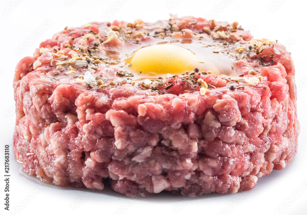磨碎的肉排或生汉堡，白色背景上有鹌鹑蛋黄和调味料。特写。