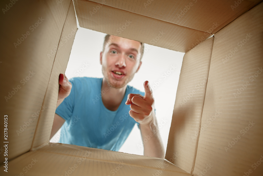 Man smiling, opening box and looking inside. The package, delivery, surprise, gift and lifestyle con