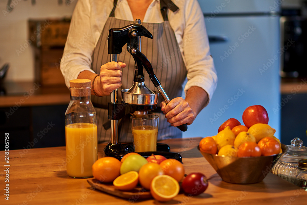 在果汁吧工作的女人。女人在榨汁机里放水果。女人在准备果汁。