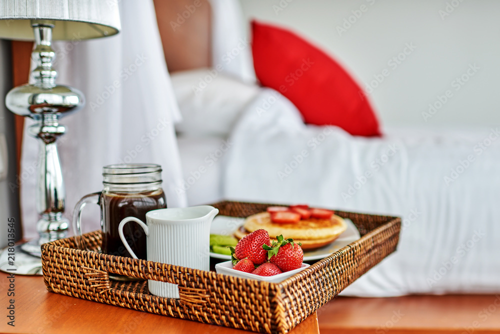 早餐在床上，托盘上放着水果和糕点。