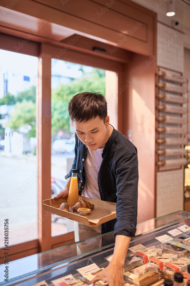 英俊的亚洲男子在下午的咖啡休息时间买面包店。面包店和咖啡休息时间。