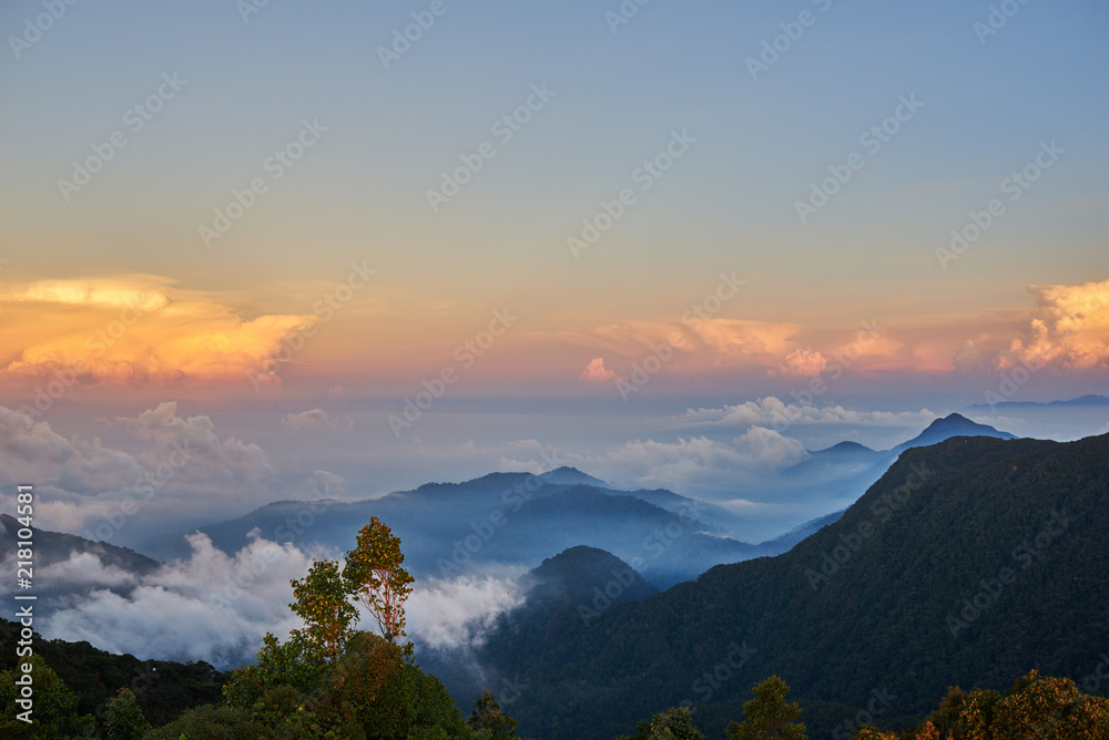 日出时的山景。从岩石、低云、蓝天和云彩上的山峰俯瞰