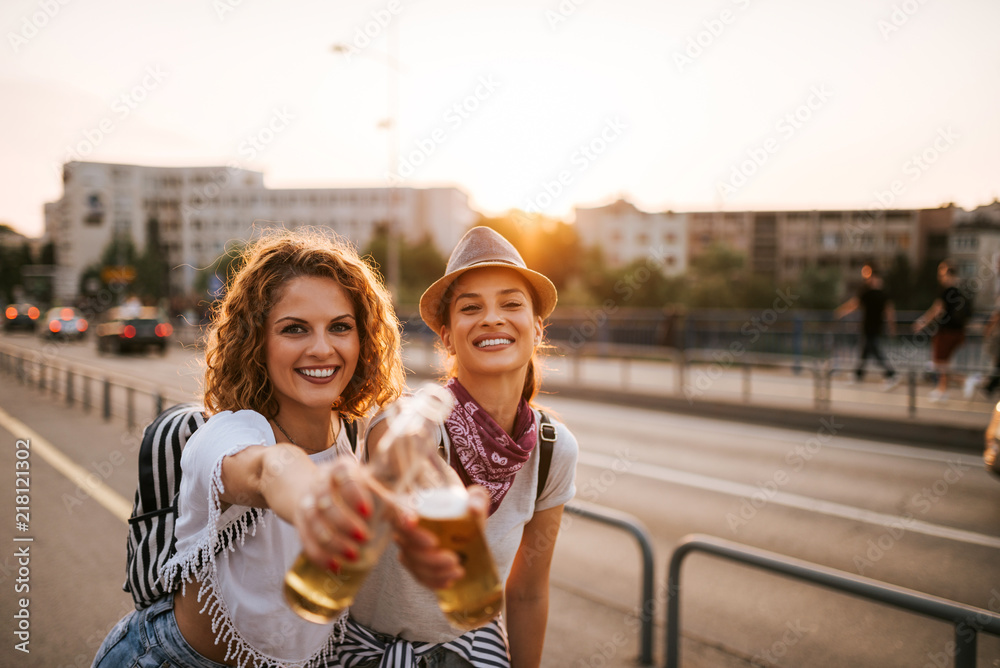 干杯！两个美丽的节日派对女孩在城市里玩得开心的画像。