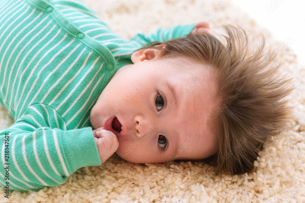 Newborn baby boy laying on the carpet in his pajamas