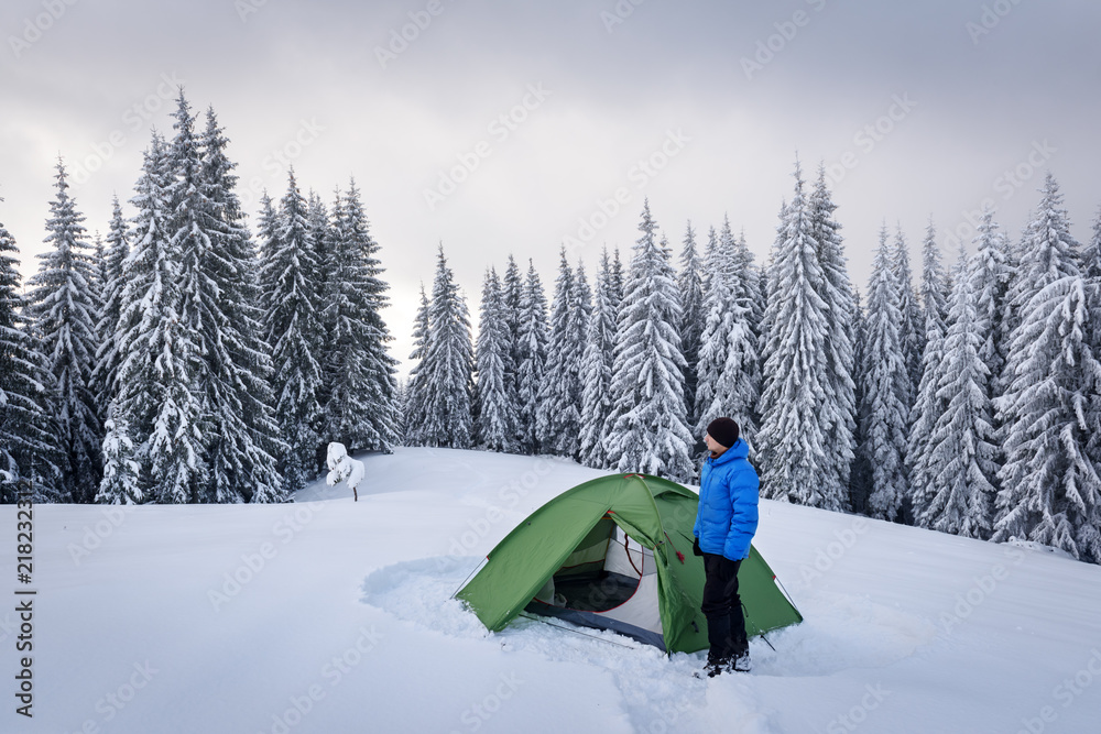 在白雪皑皑的松林背景下，绿色帐篷和游客。令人惊叹的冬季景观。Tou