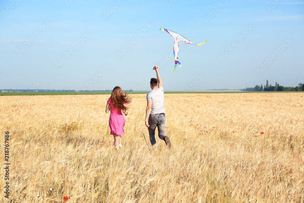 幸福的年轻情侣在田野里放风筝