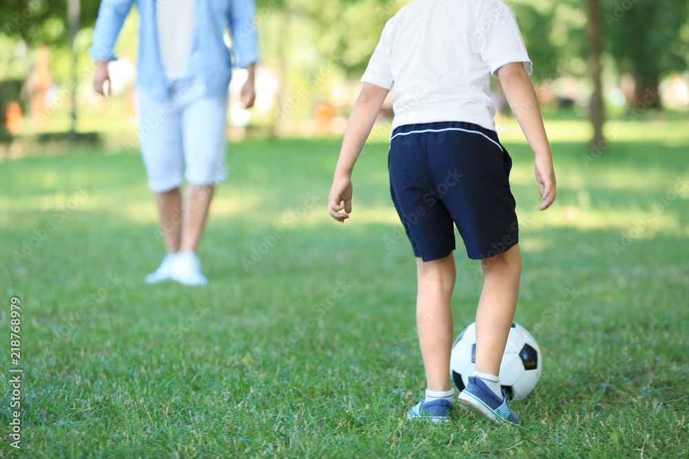 小男孩和爸爸在公园踢足球