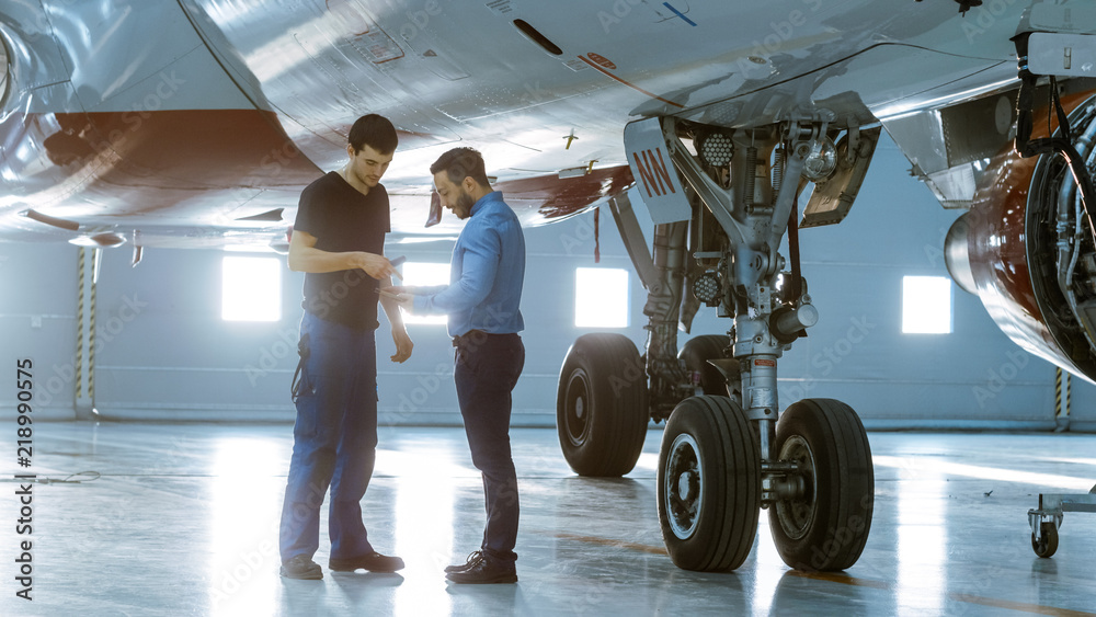 飞机维修工程师在机库向飞机技术展示平板电脑的技术数据