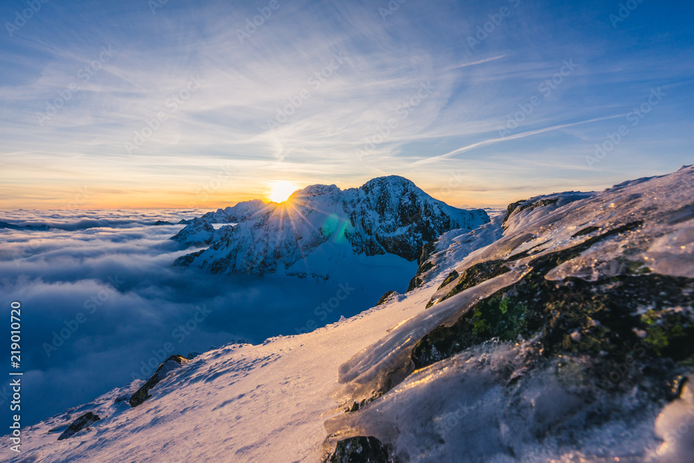 Stunning sunset or sunrise in winter alpine like snow landscape. Inversion, sun star peaking behind 