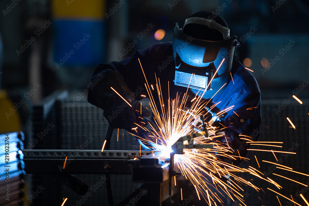 钢铁焊接厂穿着工业制服、戴着焊接铁面罩的工人，工业安全