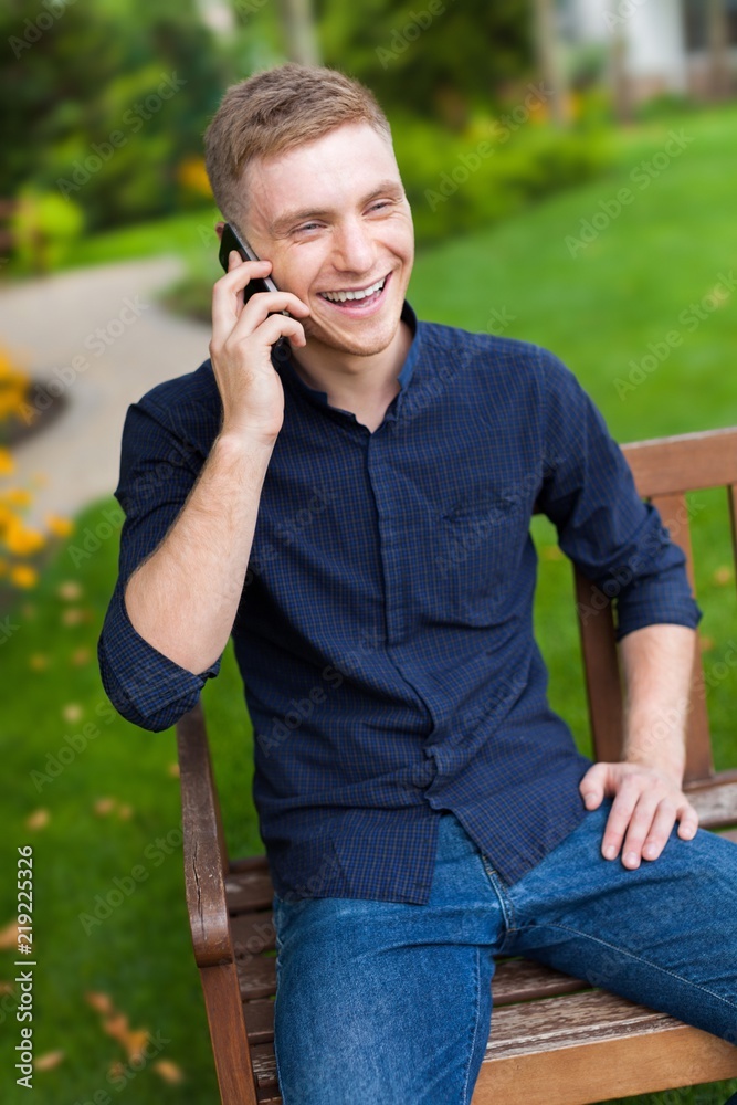 公园长椅上一个微笑的男人在打电话的肖像