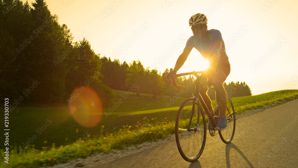 太阳耀斑：金色的阳光照亮了一个骑着公路自行车的运动员。