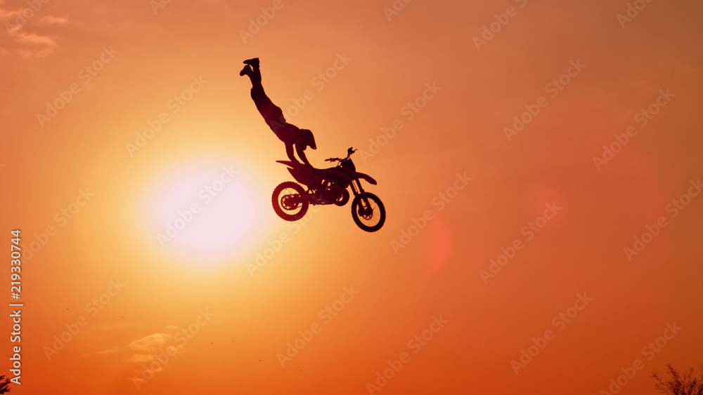 职业越野摩托车手在日落的天空中无手超人跳跃