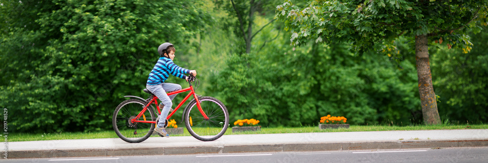 夏天孩子在柏油路上骑自行车。公园里骑自行车。男孩在美丽的su上户外骑行
