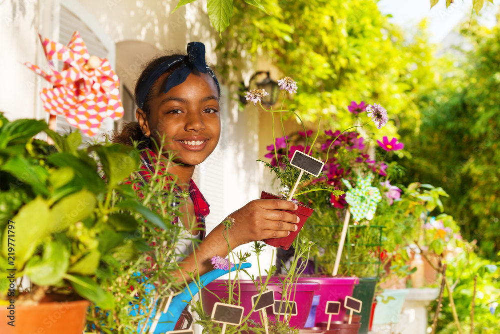 非洲女孩拿着带植物标签的花盆