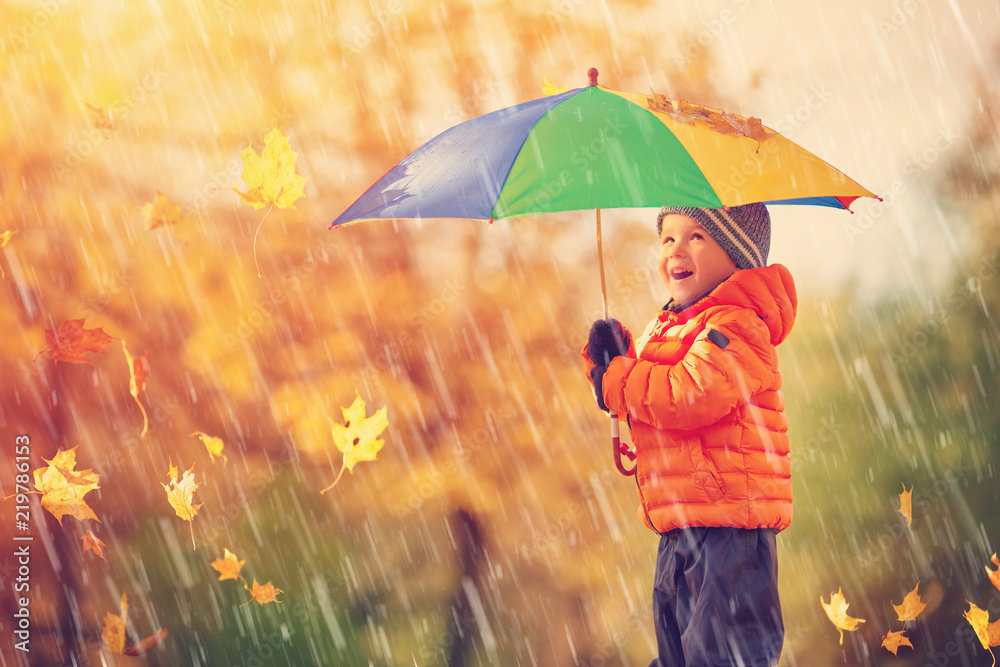 孩子撑着伞站在美丽的秋日
