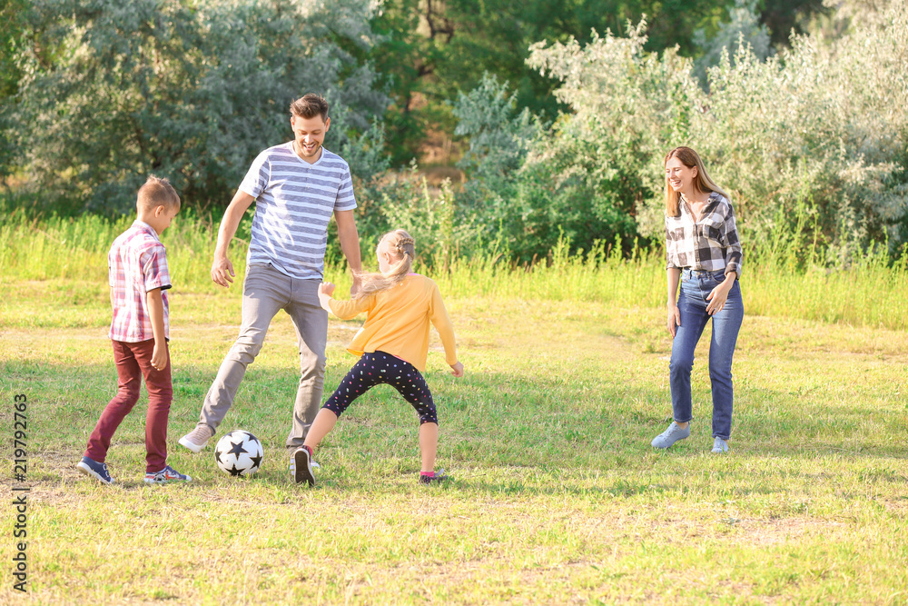 Family playing football in park on summer day