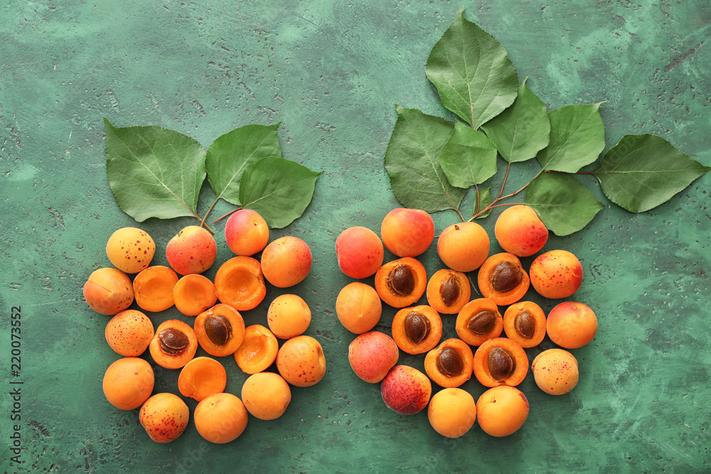 彩色桌子上的绿叶和熟甜杏子组成