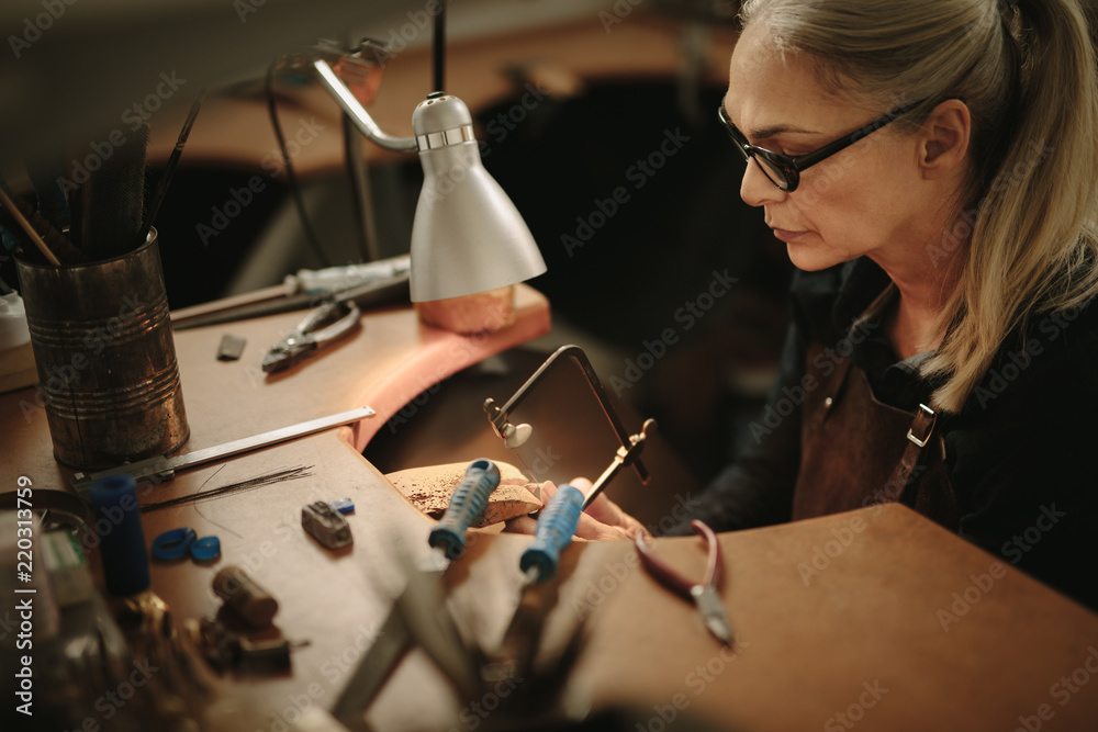 女性珠宝商在车间手工制作金属