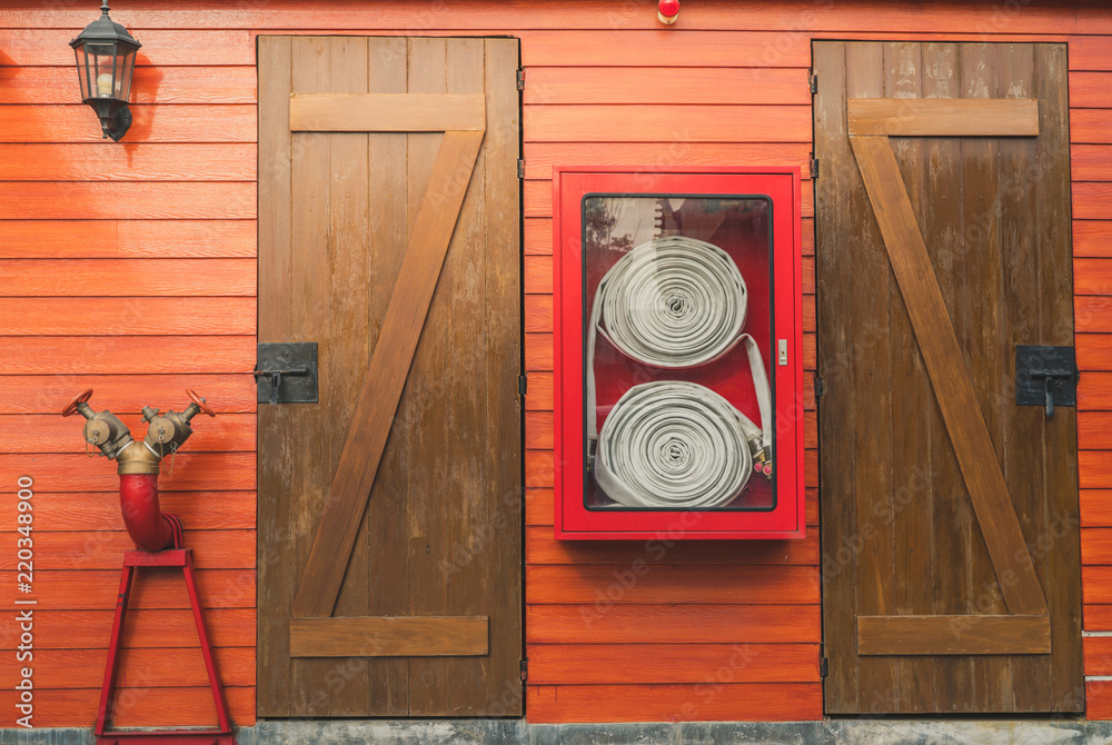 红色橱柜中的消防软管悬挂在橙色木墙上。消防应急设备箱用于安全和