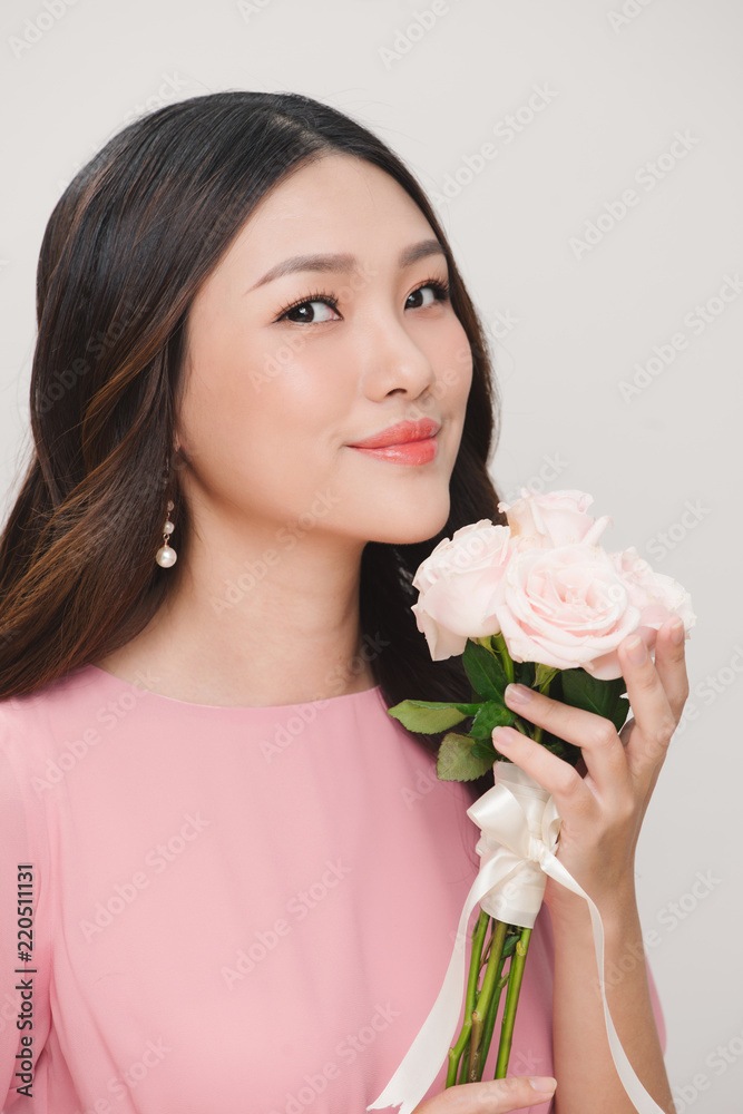 一位穿着粉色连衣裙的满意年轻女子的肖像，手里拿着一束孤立的玫瑰花