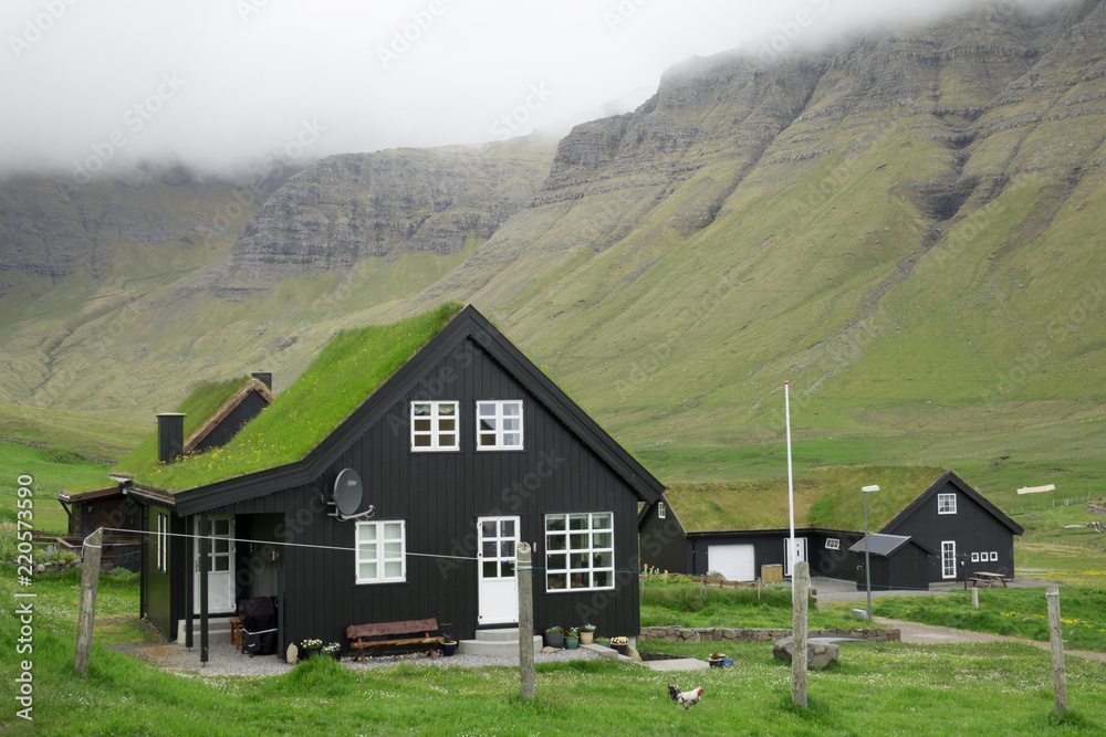 一个有着黑房子的偏远村庄坐落在群山下广阔的绿色山谷中。