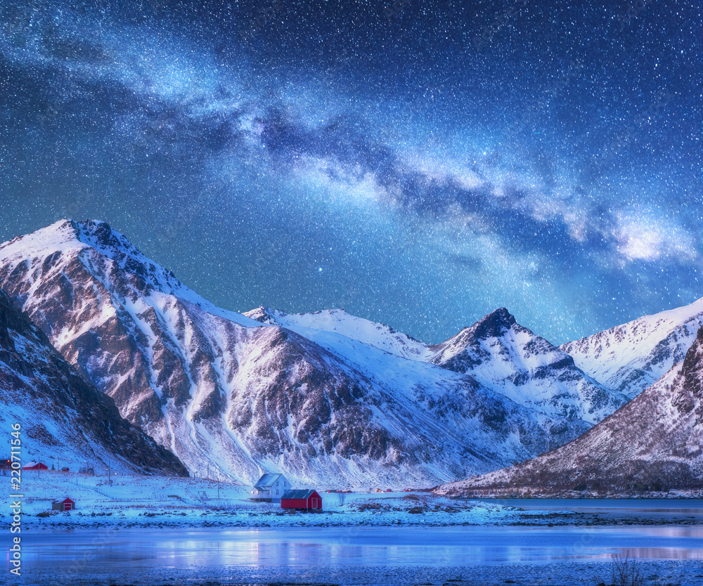 夜晚，银河在房屋和积雪覆盖的山脉上方。星空，小村庄，斯诺
