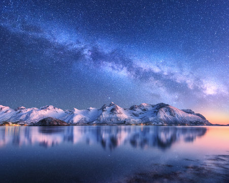 挪威冬季夜晚，明亮的银河系覆盖着白雪覆盖的山脉和海洋。带锡的风景