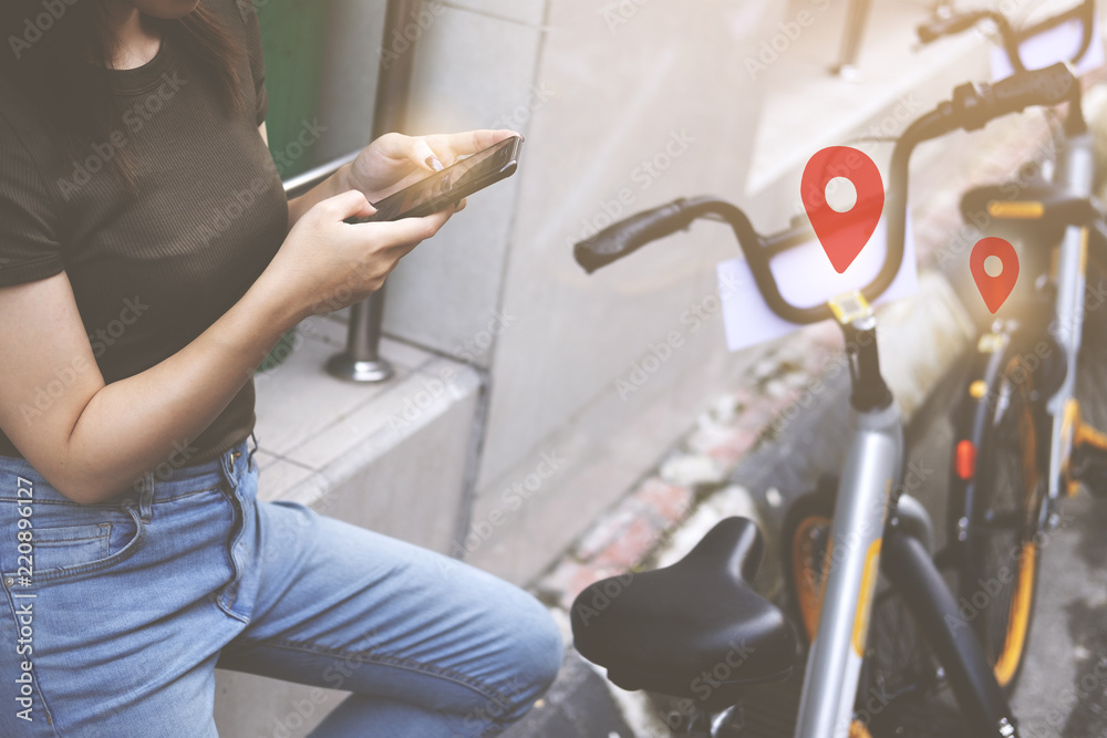 女性通过智能手机应用程序预订公共租赁自行车。