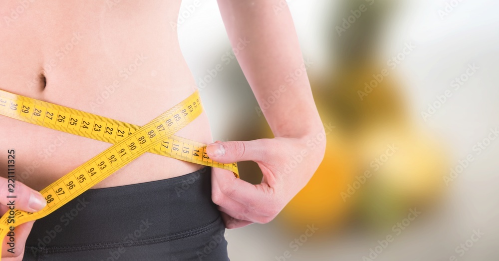Woman measuring weight with measuring tape on waist on Summer