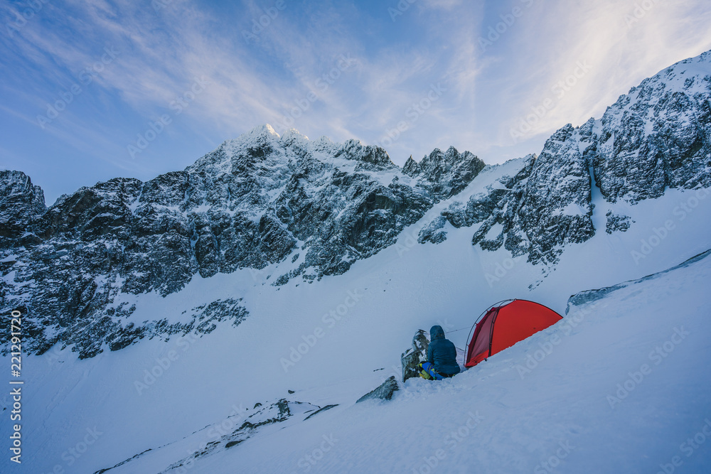 一顶红色帐篷在冬季高山景观的中部雪地上搭建。冬季露营在雪地上。高