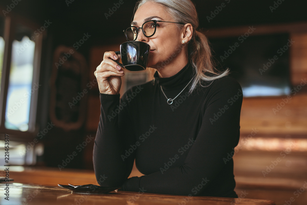 体贴的资深女性坐在咖啡馆喝咖啡