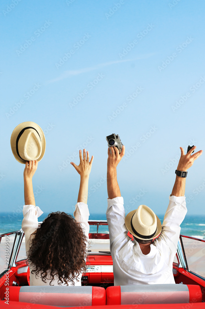 年轻夫妇坐在复古汽车里，手举着手，度假和快乐