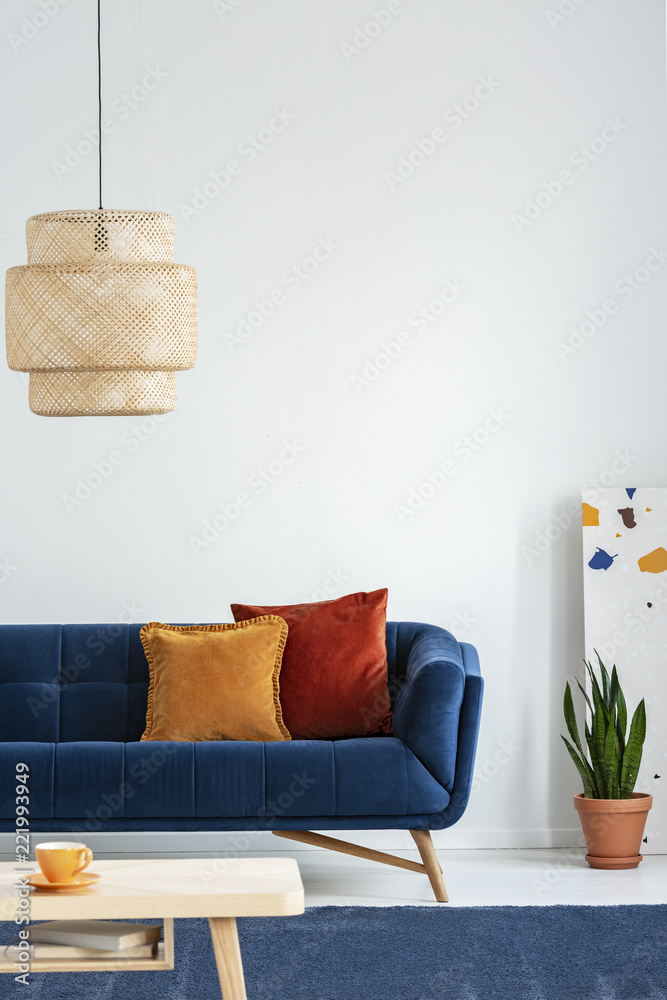 色彩斑斓的客厅里，藏蓝色地毯上一张简单的木制咖啡桌上方的复古灯罩