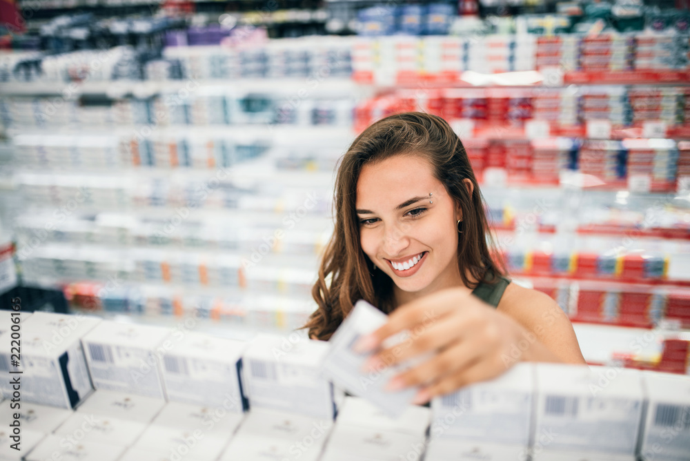 超市药店部，一名年轻女子手里拿着化妆品。