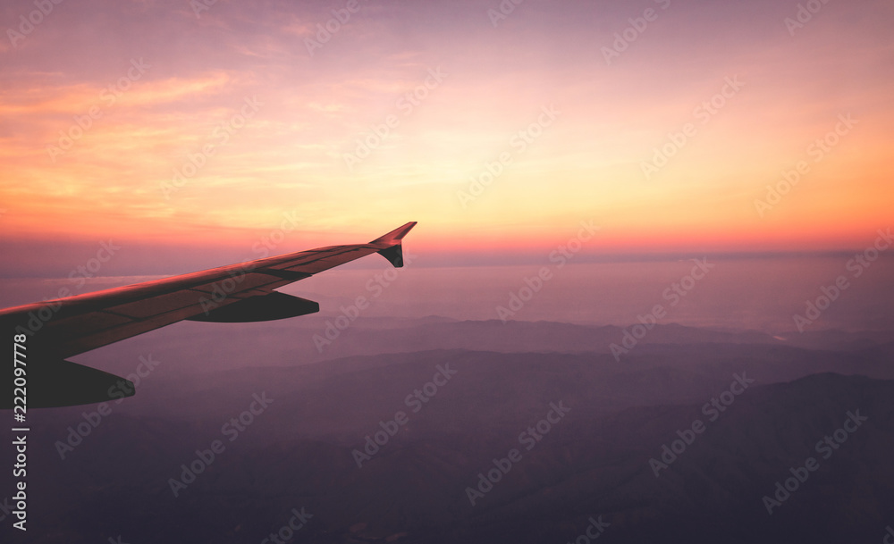 天空中的飞机机翼和日出时的山脉景观。旅行和冒险。