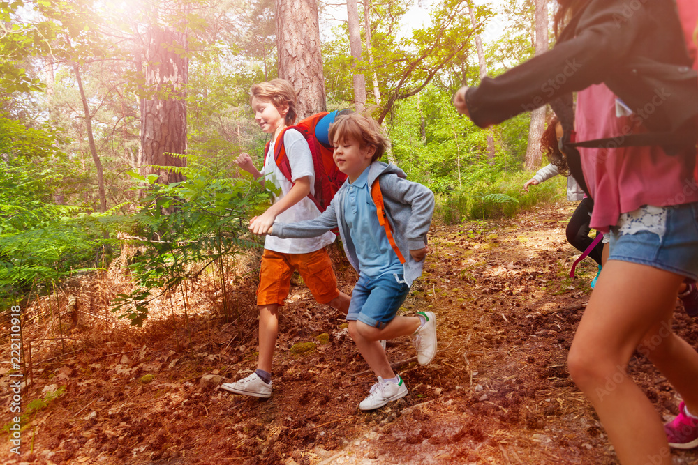 两个男孩手牵着手在森林里奔跑