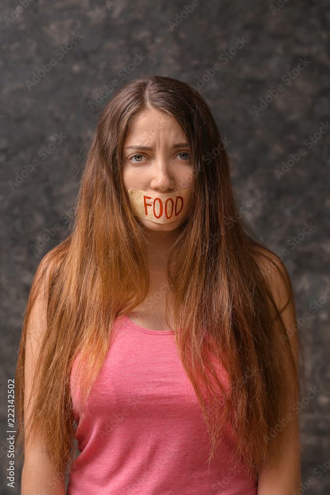 Woman with taped mouth on grey background. Diet concept