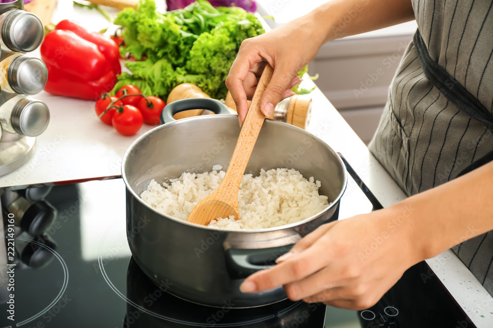 Woman cooking rice in saucepan on stove