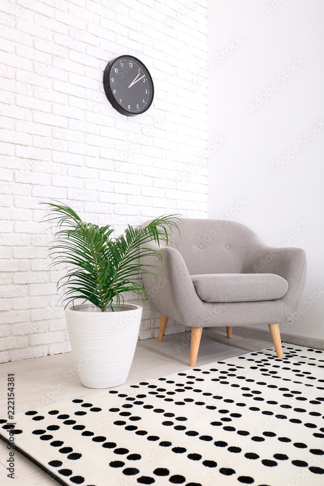 现代客厅内部，配有舒适的扶手椅和靠近砖墙的热带植物